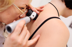 Physician looking on skin of patient with an miscroscope instrument