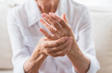 Person in white blouse holding left hand with right hand